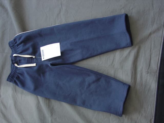 A CHILDS KNITTED PAIR OF TROUSERS FOR UNISEX. DESIGNED TO COVER THE LOWER PART OF THE BODY FROM THE WAIST TO THE ANKLE ENVELOPING EACH LEG SEPARATELY. WITHOUT AN OPENING. WITH A DRAWSTRING TIGHTENING AT THE WAIST. WITH PIPING DOWN EACH OF THE LEGS. HEMMED AT LEG ENDS. 100% COTTON. SOLD AND PACKAGED WITH A T-SHIRT CLASSIFIED SEPARATELY.