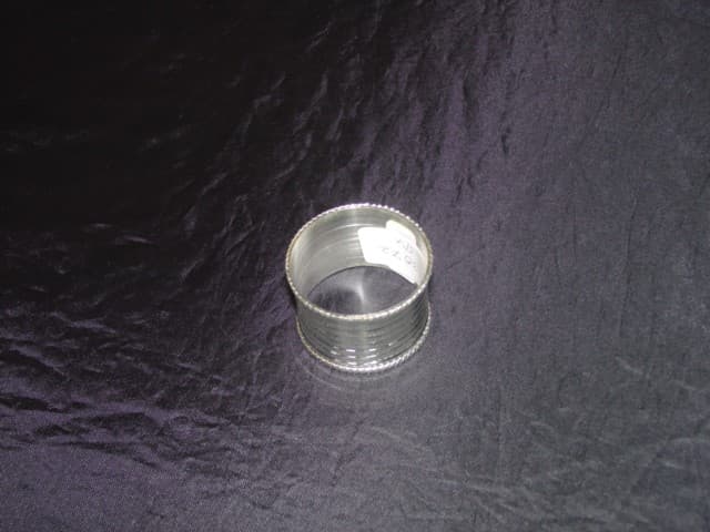 A BRASS NAPKIN RING WITH NICKEL  PLATING. USED TO HOLD A NAPKIN IN PLACE ON THE DINNER TABLE. NOT HAND MADE.
