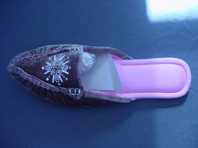 LADIES OPEN BACK SLIPPER. UPPERS OF BROWN TEXTILE MATERIAL. WITH A BEADED PATTERN ON THE VAMP. OUTER SOLE OF LEATHER.(SUEDE) NOT COVERING THE ANKLE. IN-SOLE LENGTH 24CMS OR MORE.