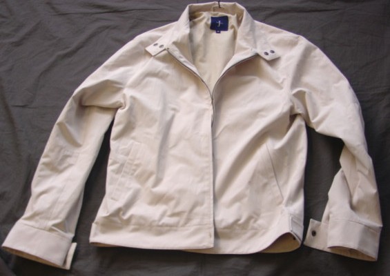 A WOVEN JACKET FOR MENS.REACHING TO BELOW THE WAIST. WITH A STAND UP  COLLAR WITH A LEFT OVER RIGHT POPPER CLOSURE. WITH A COMPLETE OPENING WITH A ZIP FASTENER. WITH LONG SLEEVES WITH POPPER FASTENING TO CUFFS. WITH SLIT POCKETS TO LOWER FRONTS. POPPER TABS TO WAISTBAND, WHICH ARE NON-ADJUSTABLE. FULLY LINED. 70% COTTON/30% NYLON.
