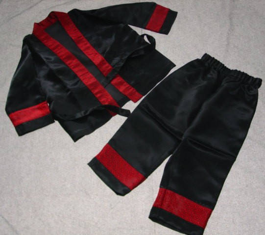 A PAIR OF SATIN WOVEN UNISEX PYJAMAS FOR CHILDREN.  THE UPPER GARMENT REACHES TO THE HIP.  WITH A COMPLETE FRONT WRAP OVER OPENING WITH A TIE FASTENING ATTACHED AT EACH SIDE OF GARMENT.  WITH LONG SLEEVES.  WITH A BAND OF CONTRASTING FABRIC AROUND OPENING AND AT WRISTS.  HEMMED AT SLEEVE ENDS AND AT BASE.  LOWER GARMENT IS A PAIR OF TROUSERS.  WITH AN ELASTICATED WAIST WITHOUT OPENING.  WITH A BAND OF CONTRASTING FABRIC ON LOWER LEGS.  HEMMED AT LEG ENDS.  50% POLYAMIDE.  50% POLYESTER.  PACKAGED IN A PAPER CARRIER BAG FOR RETAIL SALE.