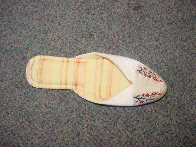 LADIES MULE STYLE SLIPPER. UPPERS OF TEXTILE MATERIAL WITH EMBROIDERED FLORAL DECORATION. OUTER SOLES OF SUEDE. INSOLE LENGTH MORE THAN 24CMS. WHITE IN COLOUR.