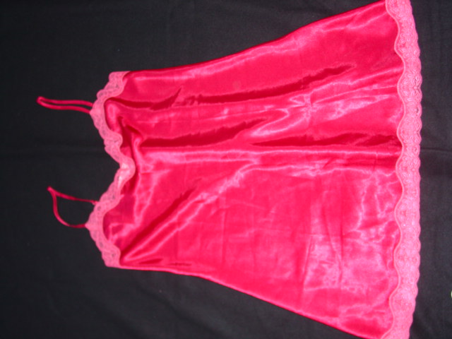 A SATIN WOVEN PETTICOAT. DESIGNED TO COVER THE BODY FROM THE SHOULDERS TO MID THIGH. WITH THIN ADJUSTABLE SHOULDER STRAPS.  WITH LACE TRIM AROUND THE TOP AND AT THE BASE OF THE GARMENT. 100% POLYESTER. DARK PINK IN COLOUR.
