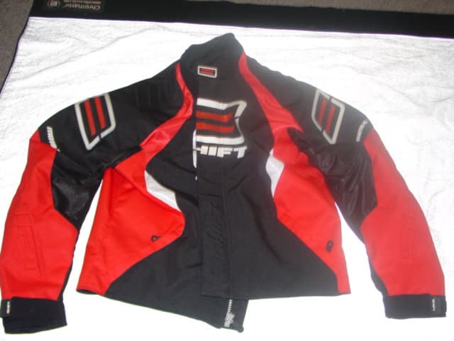 A MOTORCROSS JACKET COMPRISING OF DIFFERENT PANELS, THE MAJORITY OF WHICH ARE NOT COATED. WITH VENTED CHEST BACK AND ARM PANELS. DESIGNED TO COVER THE UPPER PART OF THE BODY TO BELOW THE WAIST.WITH A COMPLETE OPENING FASTENED WITH A ZIP WITH A PROTECTIVE FLAP FASTENING LEFT OVER RIGHT WITH VELCRO FASTENING. PRESS STUD FASTENING AT THE NECK. ZIPPED FLAP AT REAR, BOTTOM OF JACKET WHICH ALLOWS IT TO BE CONNECTED TO TROUSERS. WITH LONG SLEEVES WITH VELCRO TIGHTENING AT THE CUFFS. REMOVABLE SHOULDER AND ELBOW PROTECTOR PADS. WITH RUBBER AND REAR INJECTION LOGOS THROUGH OUT GARMENT. WITH TWO ZIPPED OUTER POCKETS TO REAR OF GARMENT. 100% POLYESTER. WITH DETACHABLE QUILTED NYLON JACKET WHICH HAS BEEN CLASSIFIED SEPARATELY. CROSS REF 113643401.