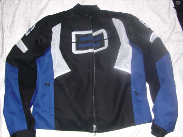 A WOVEN MEN'S JACKET. DESIGNED TO COVER THE UPPER PART OF THE BODY FROM THE SHOULDERS TO THE HIPS. DESIGNED TO BE WORN FOR PROTECTION IN MOTORCROSS. WITH PANELS OF DIFFERENT COLOURS.  WITH A COMPLETE FRONT OPENING WITH ZIP FASTENING AND A LEFT OVER RIGHT PRESS-STUD FASTENING AT THE NECK. WITH LONG SLEEVES WITH ADJUSTABLE VELCRO CUFFS. WITH TWO OUTER AND TWO INNER POCKETS. WITH EXTRA REINFORCED PANELS ON THE SHOULDERS AND ELBOWS. WITH A REMOVABLE QUILTED VEST LINER. WITH LINING. WITH PRINTED AND APPLIED LOGOS. 100% POLYESTER.