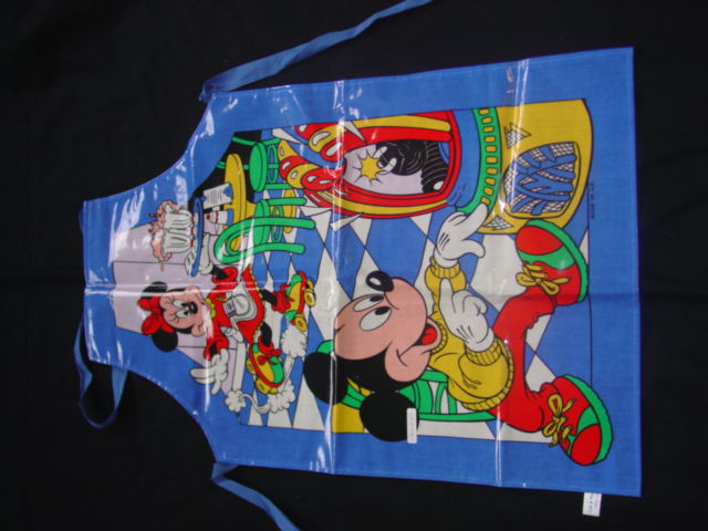WOVEN APRON. 100% COTTON FABRIC WITH PRINTED DESIGN. WITH  A POLYVINYL CHLORIDE (PVC ) COATING WHICH IS NOT CONSIDERED VISIBLE TO THE NAKED EYE. WITH A STRAP FOR WEARING AROUND THE NECK, WITH ATTACHED  STRAPS FOR FASTENING  AROUND THE BACK.