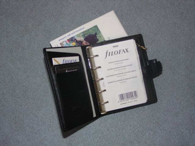 A LEATHER MINI ORGANISER.  MEASURING APPROXIMATELY 11 X 13 X 4 CMS.  THE LEATHER COVER HAS A PRESS STUD FASTENING STRAP, PEN HOLDER, POCKETS FOR CREDIT CARDS, AND A POCKET WITH A ZIP.  IT HAS A RING BINDER MECHANISM FOR RETAINING AND REMOVING INNER DIARY, INFORMATION AND ADDRESS PAGES. PRESENTED  IN  CARDBOARD PACKAGING