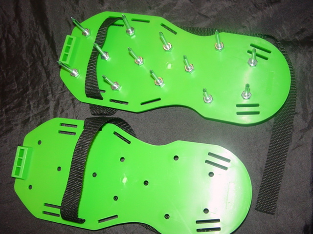 LAWN AERATOR SANDALS CONSISTING OF A MOULDED PLASTIC PLATE WITH A HEEL PART. THERE ARE HOLES IN THE PLATE TO INSERT METAL  SPIKES AND TO SECURE WITH NUTS PROVIDED. THE PLATE ALSO HAS SLOTS TO HOLD TEXTILE STRAPS. THERE IS A BUCKLE TO HOLD THE STRAP IN PLACE. THE DEVICE REVIVES CRUSTED HARDENED LAWNS AND PREPARES LAWNS FOR FERTILIZING. THE PRODUCT IS AKIN TO A TOOL OF A KIND USED FOR HORTICULTURE
