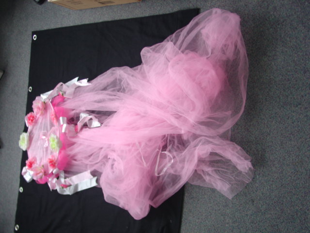 A KNITTED NET CANOPY FOR A GIRLS BED. WITH A  CIRCULAR WIRE FRAME DECORATED WITH RIBBONS AND TEXTILE FLOWERS. WITH A HANGING LOOP. OF NYLON. PACKAGED IN A POLYBAG WITH A CARDBOARD HEADER CARD.