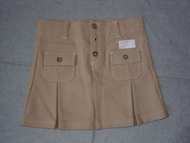 KNITTED SKIRT FOR GIRLS.  WITH PARTIAL OPENING AT FRONT FASTENED LEFT OVER RIGHT BY BUTTONS.  WITH BUTTON POCKETS ON FRONT.  WITH TWO PLEATS ON LOWER FRONT.  HEMMED AT BASE.  96% COTTON AND 4% MAN MADE FIBRES