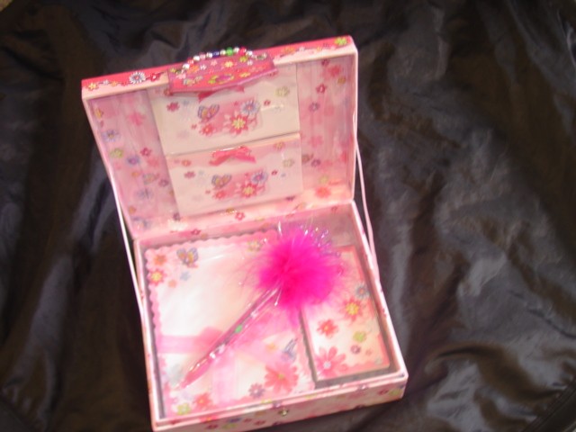 STATIONERY SET FOR CHILDREN. COMPRISES OF A SQUARE PAPERBOARD BOX WITH STUD FASTENER, DECORATED WITH GLITTER, BEADS AND PAPER DIE CUT SHAPES. CONTENTS ARE 8 ENVELOPES DECORATED WITH RIBBON, 8 SHEETS OF WRITING PAPER AND 8 ENVELOPES, 1 NOTEPAD, AND 1 PEN DECORATED WITH MARABOU FLUFF AND PLASTIC CROWN ATTACHED BY A SPRING. PACKAGED FOR RETAIL SALE IN A TRANSPARENT CELLOPHANE BAG.