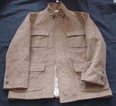 A WOVEN CORDUROY JACKET FOR MEN.  DESIGNED TO COVER THE BODY FROM THE SHOULDERS TO THE UPPER THIGH.  FULLY LINED.  WITH A COMPLETE FRONT OPENING WITH A ZIP FASTENING.  WITH A LEFT OVER RIGHT STORM FLAP WITH A POPPER FASTENING AND A TWO BUTTON FASTENING AT THE TOP.  WITH AN APPLIED STAND UP COLLAR.  WITH LONG SLEEVES WITH A TWO BUTTON FASTENING AT THE CUFF (NOT A TIGHTENING). WITH A BREAST POCKET EACH SIDE AND A LOWER POCKET EACH SIDE,  ALL WITH FLAPS.  WITH TWO INSIDE POCKETS.  HEMMED AT SLEEVE ENDS AND AT BASE.  100% COTTON.  PACKAGED ON A HANGER IN A POLYBAG FOR RETAIL SALE.