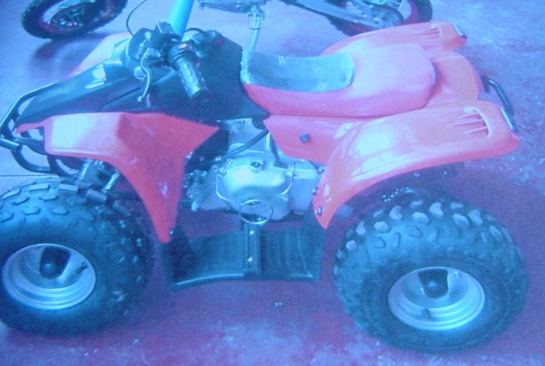 A 50CC PETROL QUAD BIKE.  IT HAS AN ORANGE AND BLACK BODY.