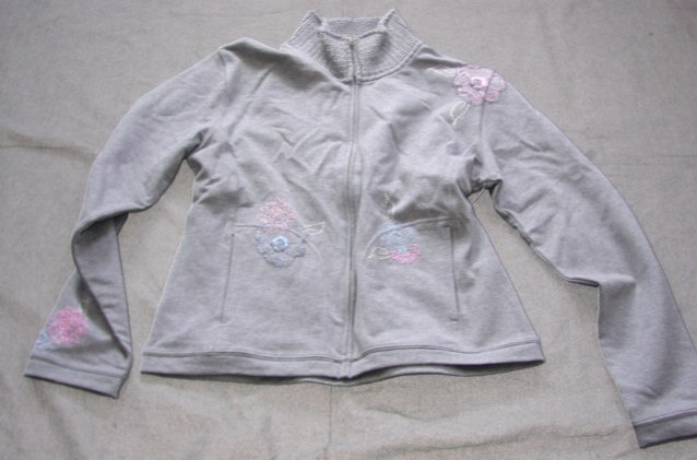 A KNITTED JACKET FOR UNISEX.  DESIGNED TO COVER THE UPPER PART OF THE BODY FROM THE SHOULDERS TO THE HIP.   WITH A COMPLETE FRONT OPENING FASTENED BY A ZIP WHICH EXTENDS TO THE TOP OF AN ATTACHED THICKER KNITTED COLLAR.  WITH LONG SLEEVES.  WITH A VERTICAL POCKET EACH SIDE ON LOWER FRONT.  WITH AN EMBROIDERED FLORAL DESIGN ON FRONT.  HEMMED AT BASE.  83% COTTON.  12% POLYESTER.  5% ELASTANE.