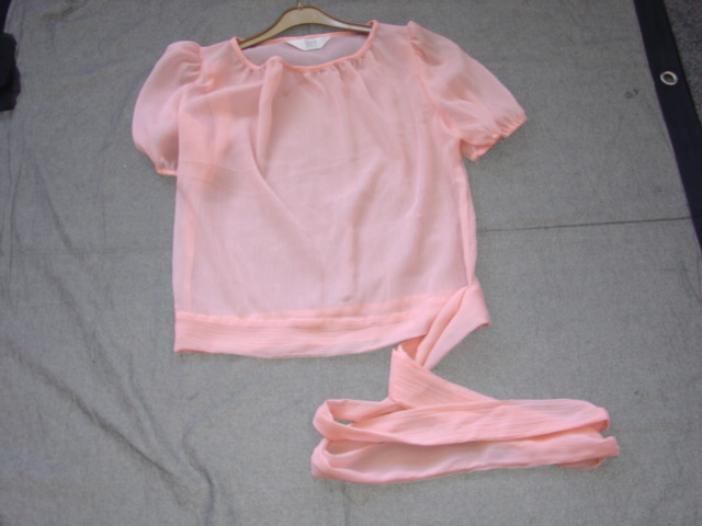 A WOVEN GARMENT FOR WOMEN. COVERING THE UPPER HALF OF THE BODY. WITH A ROUND NECK. WITH SHORT PUFFED SLEEVES, WITH ELASTIC AT SLEEVE ENDS. GATHERED ONTO A WELT AT THE BASE OF THE GARMENT, WHICH HAS A SPLIT AND POPPER  TO LEFT HAND SIDE. WELT HAS LONG ENDS WHICH TIE INTO A BOW. 100% SILK