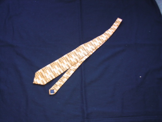 A WOVEN POLYESTER NECK TIE. PRINTED WITH VARIOUS SLOGANS. PACKAGED IN A TIN.