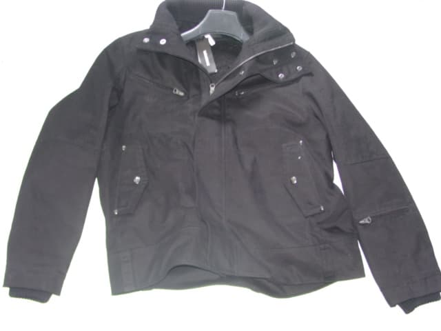 A WOVEN JACKET FOR MEN. REACHING TO THE WAIST. WITH A COMPLETE OPENING WITH A ZIP FASTENER AND A LEFT OVER RIGHT PLACKET WITH POPPERS. WITH A RIBBED COLLAR, WITH POPPERS TO NECK. WITH LONG SLEEVES, HEMMED AT SLEEVE ENDS, WITH INNER RIBBED CUFFS. CURVED HEM TO BASE OF GARMENT WITH DECORATIVE BELT LOOPS. ONE ZIP PCKET TO SLEEVE AND TWO TO CHEST. TWO LOWER POCKETS WITH POPPER FLAPS. FULLY LINED.  OF 68% NYLON / 32% COTTON.
