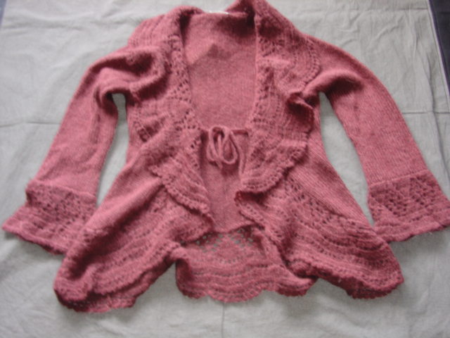 A KNITTED CARDIGAN FOR WOMEN.  DESIGNED TO COVER THE UPPER PART OF THE BODY FROM THE SHOULDERS TO THE TOP OF THE THIGH.  WITH A COMPLETE OPENING WITH A TIE FASTENING AT FRONT.  WITH LONG SLEEVES WITH AN APPLIED WIDE PATTERNED CUFF.  WITH AN APPLIED  PATTERNED SCALLOPED BORDER AROUND GARMENT MEASURING 14 CMS. WIDE APPROX..  FORMING A COLLAR AT THE TOP.  30% MOHAIR.  30% WOOL.  40% NYLON.