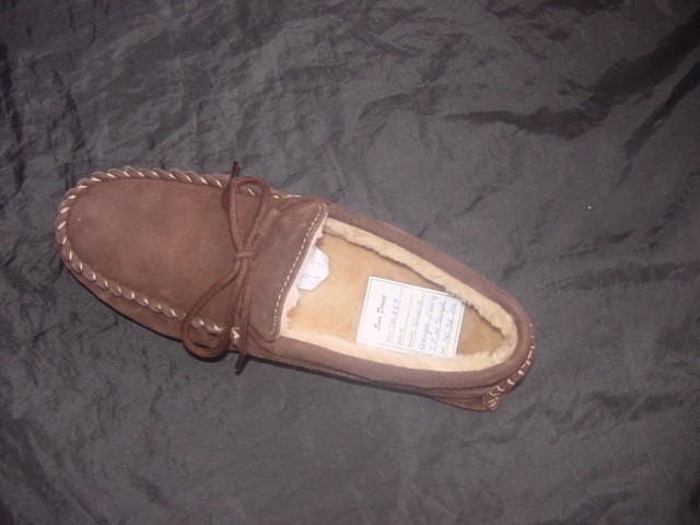 A MOCCASIN STYLE INDOOR SLIPPER. UPPERS OF BROWN LEATHER(SUEDE) LINED WITH IMITATION FUR MATERIAL. LACE TIE AT THE FRONT. NOT COVERING THE ANKLE. STITCH DETAIL AROUND THE EDGE AND ON THE HEEL. IN-SOLE LENGTH EXCEEDS 24CMS. OUTER SOLE OF PLASTIC/RUBBER MATERIAL AND TEXTILE. THE TEXTILE MATERIAL IS CONSIDERED TO HAVE SUBSTANTIAL WEARING PROPERTIES CONFIRMED BY THE MARTINDALE ABRASION TEST.