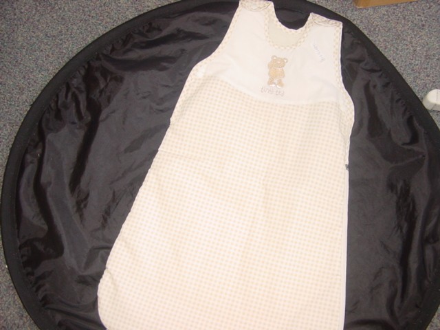 A WOVEN BABIES GARMENT WITH KNITTED LINING INTENDED TO ENCASE THE BODY AND BOTH LEGS WITH COMPLETE OPENING AROUND BASE AND UP ONE SIDE. WITH ZIP FASTENING. WITH PRESS STUDS ON THE SHOULDERS AND AT THE SIDE. WITH ROUND NECKLINE. THE GARMENT IS DESIGNED SO AS TO ENCASE BOTH LEGS TOGETHER.UPPER PART WITH A CHECK DESIGN AND BEAR MOTIF. DESIGNED FOR BABIES AGED FROM 0 TO 6 MONTHS AND 6 TO 12 MONTHS