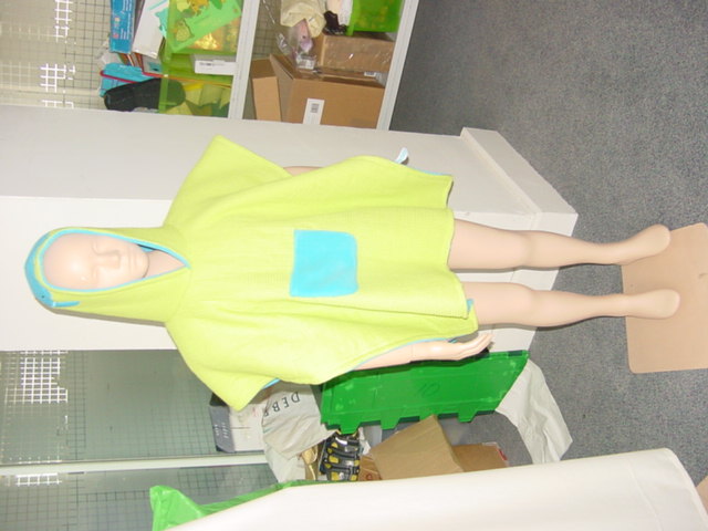 A WOVEN COTTON BATH ROBE FOR A CHILD. WITH A WAFFLE COTTON OUTER AND A FLEECE COTTON INNER. WITH A POCKET IN THE FRONT CENTRE. WITH A HOOD WITH APPLIED DECORATION. WORN LIKE A PONCHO.