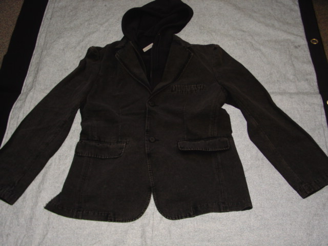A WOVEN JACKET FOR MEN.  DESIGNED TO COVER THE UPPER PART OF THE BODY FROM THE SHOULDERS TO THE UPPER THIGH.  WITH A COMPLETE OPENING WITH A REVER COLLAR AND A LEFT OVER RIGHT TWO BUTTON FASTENING.  WITH LONG SLEEVES WITH DECORATIVE BUTTONS ON CUFF.  WITH A POCKET WITH FLAP EACH SIDE ON LOWER FRONT.  WITH A LEFT HAND  BREAST POCKET.  WITH CENTRE BACK VENT.  WITH A KNITTED HOOD WITH DRAWSTRING TIE.  WITH KNITTED INSERT EACH SIDE OF CENTRE FRONT WITH A ZIP FASTENING.   HEMMED AT SLEEVE ENDS AND AT BASE.  100 PERCENT COTTON.