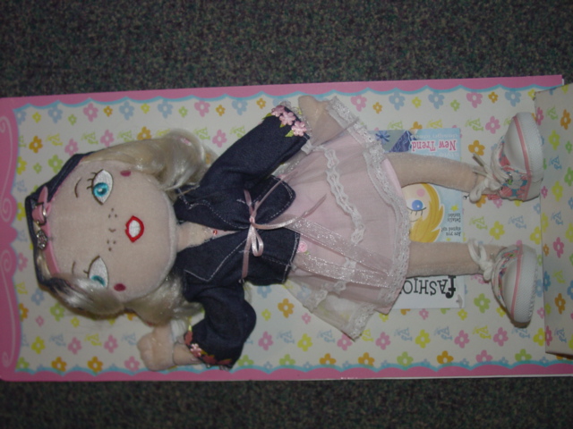 STUFFED DOLL MADE OF TEXTILE MATERIALS.  REPRESENTING A HUMAN BEING. DRESSED IN A DENIM JACKET AND A PINK SKIRT. WITH COLOURED PLIMSOLES ON HER FEET. WITH A DENIM HAT. MEASURING  APPROX. 36.5CM.