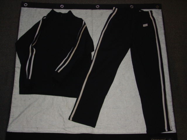 A KNITTED TRACKSUIT FOR UNISEX  CONSISTING OF AN UPPER AND LOWER GARMENT. THE UPPER GARMENT HAS A COMPLETE OPENING FASTENED WITH A ZIP WHICH EXTENDS UP INTO THE COLLAR. WITH LONG SLEEVES WITH RIBBED CUFFS AND TWO CONTRASTING STRIPES RUNNING FROM THE TOP OF THE SHOULDER DOWN EACH ARM. WITH A POCKET ON EACH FRONT PANEL AND RIBBING TO BASE OF GARMENT. WITH INNER SURFACE NAPPED. THE LOWER GARMENT IS A PAIR OF LOOSE FITTING TROUSERS WHICH ENVELOP EACH LEG SEPARATELY TO THE ANKLE. WITH  AN ELASTICATED WAIST WITHOUT OPENING AND  WITH A DRAWSTRING TIE. HEMMED. WITH TWO HIP POCKETS AND A BACK POCKET WITH ZIP CLOSURE. WITH TWO CONTRASTING STRIPES DOWN EACH OUTSIDE LEG. WITH INNER SURFACE NAPPED.  65 PER CENT POLYESTER, 35 PER CENT COTTON.