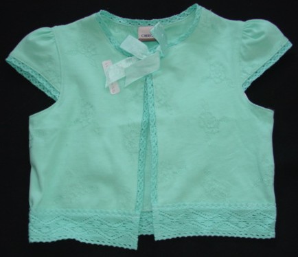 A KNITTED JACKET FOR A GIRL.  DESIGNED TO COVER THE UPPER PART OF THE BODY FROM THE SHOULDERS TO BELOW THE WAIST.  WITH A ROUND NECK.  WITH A COMPLETE OPENING WITH A BUTTON FASTENING AT THE TOP COVERED BY A DECORATIVE RIBBON BOW.  WITH CAP SLEEVES.  WITH EMBROIDERED DESIGN ON GARMENT.  WITH DECORATIVE EDGING AROUND NECK EDGE, SLEEVE ENDS,  EACH SIDE OF FRONT AND AROUND BASE OF GARMENT.  100 PERCENT COTTON.