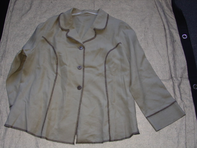 WOVEN JACKET FOR WOMEN.  REACHING DOWN TO BELOW THE WAIST.  V NECK WITH COLLAR.  COMPLETE FRONT OPENING FASTENED RIGHT OVER LEFT BY BUTTONS.  LONG SLEEVES WITH CUFFS.  ALL EDGES OVERSEWN BY CONTRASTING YARN.  100 PERCENT LINEN