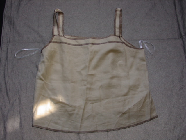 WOVEN BLOUSE FOR WOMEN.  REACHING DOWN TO BELOW THE WAIST.  SQUARE NECK WITHOUT OPENING.  WITHOUT SLEEVES. ALL EDGES OVERSEWN WITH CONTRASTING YARN.  SMALL VENTS IN SIDE SEAMS AT BASE.  100 PERCENT LINEN