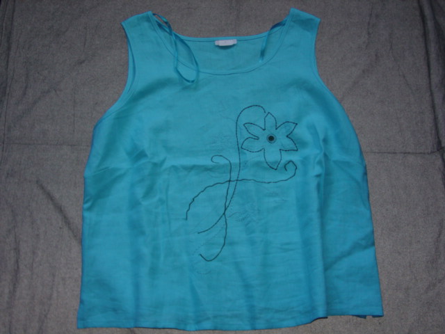 WOVEN BLOUSE FOR WOMEN. REACHING DOWN TO BELOW THE WAIST.  ROUND NECK WITHOUT OPENING.  WITHOUT SLEEVES.  HEMMED AT BASE WITH SMALL VENTS IN SIDE SEAMS.  EMBROIDERED DESIGN ON FRONT. 100 PERCENT LINEN