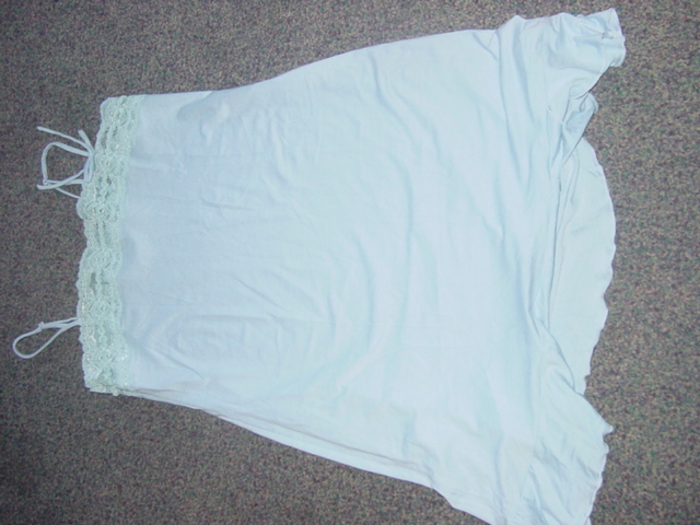 WOMENS KNITTED NIGHTDRESS. WITH THIN ADJUSTABLE SHOULDER STRAPS. DESIGNED TO COVER UPPER PART OF THE BODY FROM THE SHOULDERS TO MID THIGH. WITH LACE TRIM AROUND THE TOP AND A SMALL BOW ATTACHED TO SHOULDER STRAP. FLUTED HEM AROUND THE BOTTOM. BLUE IN COLOUR. OF MAN MADE FIBRE.