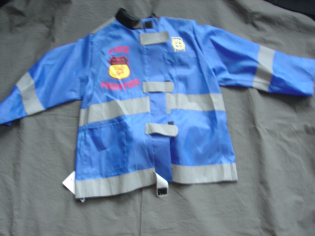 WOVEN NYLON JACKET FOR CHILDREN. PART OF A FANCY DRESS FIREFIGHTERS OUTFIT. WITH A COMPLETE OPENING WITH A LEFT OVER RIGHT VELCRO CLOSURE AT COLLAR, WITH VELCRO TABS FASTENING RIGHT OVER LEFT. WITH HIGH VISIBILITY STRIPS. WITH LONG SLEEVES. HEMMED AT SLEEVE ENDS. OVERLOCKED AT BASE OF GARMENT. WITH A POCKET BELOW THE WAIST. WITH PRINTED BADGES TO FRONT AND A DETACHABLE FOAM CYLINDER TO THE BACK. OF NYLON. PACKAGED WITH A PAIR OF TROUSERS AND A HAT.CLASSIFIED SEPARATELY. CROSS REF 115592964 AND 115541008.