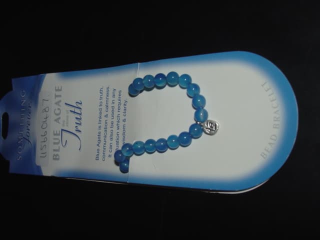 BLUE AGATE STONE BRACELET WITH SMALL ACCESSORY ATTACHED. ON ELASTICATED STRING WITH NO FASTENINGS. PACKAGED ON A CARDBOARD HANGER WITH DESCRIPTION OF BRACELET AND DETAILS OF THE STONE.