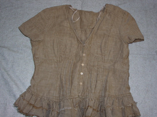 WOVEN BLOUSE FOR WOMEN.  REACHING DOWN TO BELOW THE WAIST.  V-NECK.  COMPLETE FRONT OPENING FASTENED RIGHT OVER LEFT BY BUTTONS.  SHORT SLEEVES.  HEMMED AT SLEEVE ENDS.  FRILL GATHERED HEM, FRAYED.  WITH PIN TUCK DETAIL AT FRONT.  100 PERCENT LINEN.