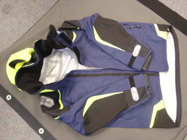 A WOVEN COAT FOR MEN COVERING THE UPPER BODY FROM THE SHOULDERS TO THE HIPS. WITH A COMPLETE FRONT OPENING WITH A ZIP FASTENER AND LEFT OVER RIGHT STORM FLAP. WITH A COLLAR WITH A CONCEALED HOOD, WITH DRAWSTRING. WITH LONG SLEEVES WITH INNER RUBBER CUFFS AND VELCRO TIGHTENING ON BOTH INNER AND OUTER CUFF. WITH TWO SIDE POCKETS WITH ZIP CLOSURES. WITH REFLECTIVE PATCHES ON EACH SHOULDER AND CUFF. WITH ELASTICATED DRAWSTRING AND TOGGLE TIGHTENING AND HEMMED AT BASE OF GARMENT. NYLON WITH A PU COATING THAT IS DEEMED TO BE VISIBLE TO THE NAKED EYE.