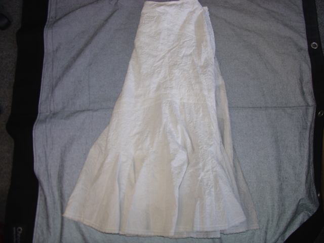 LADIES WOVEN SKIRT.  REACHING DOWN TO BELOW THE KNEE.  WITH A BOUND WAIST. WITH A ZIPPED OPENING. WITH HOOK AND EYE FASTENING AT THE TOP. WITH LACE DETAIL AROUNDTHE BASE. EMBROIDERED FABRIC. COLOUR WHITE.  100 PERCENT COTTON. FULL LINING 100 PERCENT COTTON.