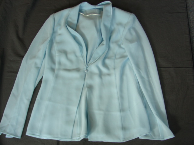 WOVEN JACKET FOR WOMEN.  REACHING DOWN TO BELOW THE WAIST.  V-NECK WITH COLLAR DECORATED WITH SATIN TRIM AND BEADING.  COMPLETE FRONT OPENING FASTENED RIGHT OVER LEFT BY SINGLE BUTTON.  LONG SLEEVES. HEMMED AT SLEEVE ENDS AND AT BASE.  LINED.  WITH SHOULDER PADS.  100 PERCENT POLYESTER
