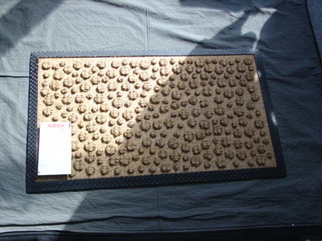 A WOVEN DOORMAT OF COIR. WITH A RUBBER SURROUND AND BACKING. WITH A PILE DESIGN OF SMALL CIRCLES OF DIFFERING SIZES. MEASURING 45 X 75 CMS.