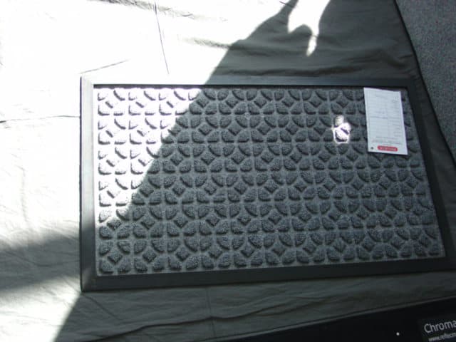 A WOVEN POLYPROPYLENE DOOR MAT, WITH A PILE SURFACE IN A CIRCLES PATTERN. WITH A RUBBER SURROUND AND BACKING.