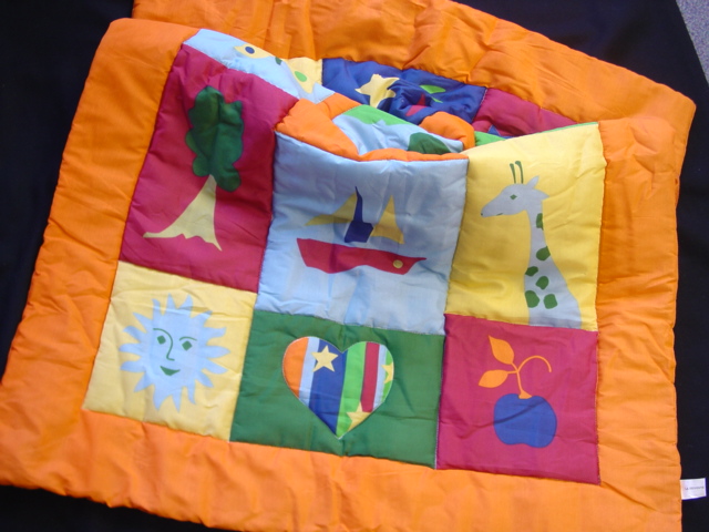 QUILTED BLANKET SIMILAR TO PADDED EIDERDOWN.   WITH  PANELS OF DIFFERENT BRIGHT COLOURED IMAGES ON ONE SIDE.  OF 80 PERCENT POLYETER AND 20 PERCENT COTTON.  INTERNAL WADDING OF POLYESTER. PACKED IN A PLASTIC BAG.