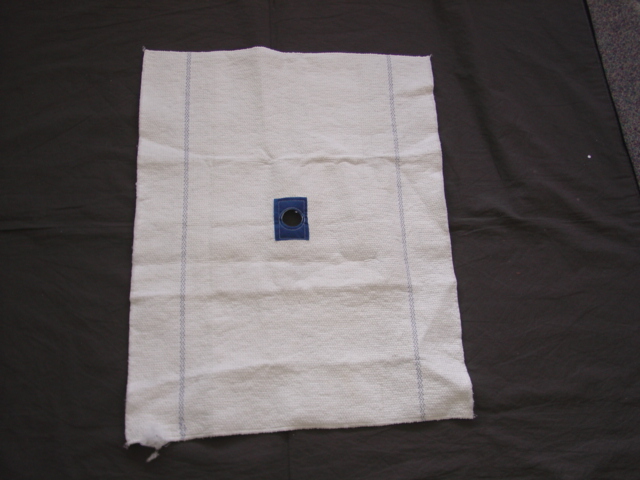 A FLOOR CLOTH OF 80 PERCENT COTTON AND 20 PERCENT SYNTHETIC FIBRES. MEASURING 65 X 50 CMS. WITH CONTRASTING ROWS OF STITCHING AND A REINFORCED HOLE IN THE CENTRE. CONSTRUCTED FROM A LAYER OF WADDING STITCHED TO A LAYER OF NONWOVEN, OVERLOCKED ON SHORT EDGES.