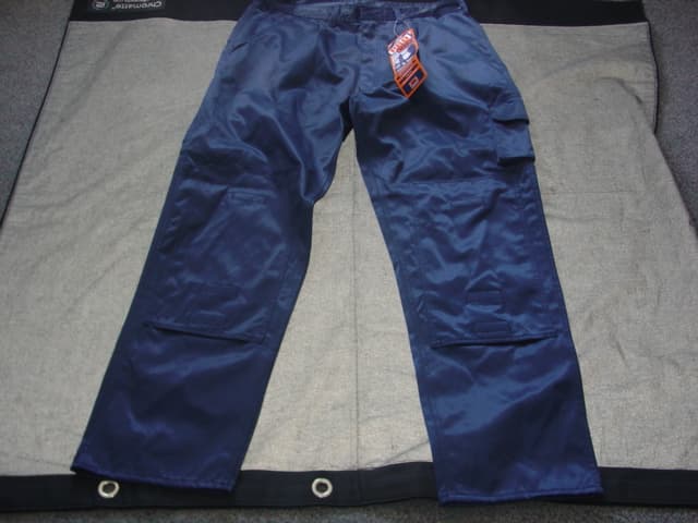 A PAIR OF WOVEN TROUSERS FOR MEN FOR INDUSTRIAL/OCCUPATIONAL USE. DESIGNED TO COVER THE LOWER PART OF THE BODY ENVELOPING EACH LEG SEPARATELY. MADE OF A HARD WEARING FABRIC. WITH DOUBLE STITCHED SAFETY SEAMS. WITH ATTACHED WAISTBAND WITH SEVEN BELT LOOPS. WITH ZIP FLY FASTENING AND METAL BUTTON FASTENING AT WAISTBAND WHICH FASTENS LEFT OVER RIGHT. WITH SLIT POCKETS ON EITHER SIDE AT HIP LEVEL, OF A STRONG FABRIC. WITH PATCH POCKETS FASTENED WITH VELCRO TO BACK OF GARMENT. WITH ADJUSTABLE KNEE PAD POCKETS FASTENED WITH VELCRO, BELLOWED LEG POCKET FASTENED WITH VELCRO AND TOOL POCKET TO UPPER LEGS.  HEMMED AT LEG ENDS. MADE FROM 50 PER CENT POLYESTER AND 50 PER CENT COTTON.