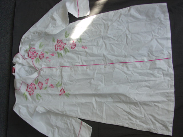 WOVEN NIGHTSHIRT STYLE NIGHTDRESS FOR WOMEN.   REACHING DOWN TO BELOW MID THIGH.  V-NECK WITH COLLAR.  COMPLETE FRONT OPENING FASTENED RIGHT OVER LEFT BY BUTTONS.  LONG SLEEVES.  WITH CONTRAST PIPING TRIM AROUND COLLAR, FRONT OPENING AND CUFF AT SLEEVE ENDS.  HEMMED AT BASE WITH VENTS IN SIDE SEAMS. WITH LARGE FLORAL EMBROIDERY ON FRONT.  OF COTTON