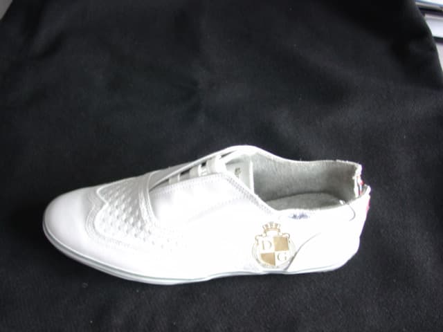 A  CASUAL SHOE FOR MEN. WITH A CONCEALED LACING. WITH A BROGUE STYLE DETAILING. WITH AN EVA MIDSOLE.  WITH EMRBOIDERED LOGO TO HEEL AND TONGUE,  AND PRINTED LOGO TO SIDE OF SHOE. PLAIN WHITE LEATHER WITH A MUTILCOLOURED STRIPED RUBBER TRIM ROUND EDGE OF SOLE.WITH A KNITTED TEXTILE LINING.