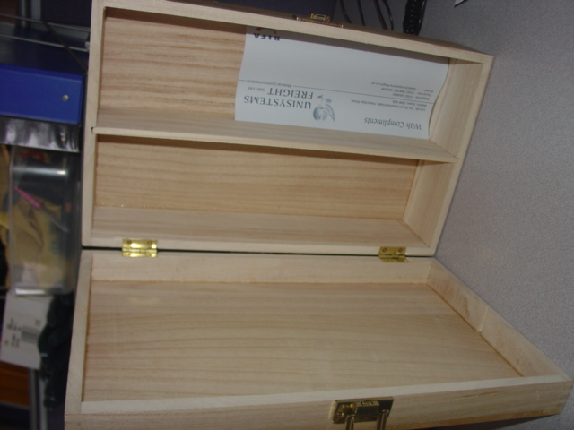 A PLAIN WOODEN BOX FOR THE TRANSPORTATION AND PACKAGING OF BOTTLES. WITH BRASS EFFECT HINGES AND CLASP. INSIDE THE BOX IS SHAPED TO HOLD 2 BOTTLES. MEASURES 35CM x 21CM APPROX. MADE FROM PAULOWINA WOOD.