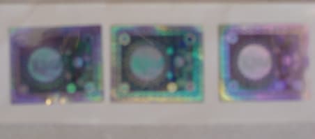 HOLOGRAPHIC SELF ADHESIVE LABELS.  THE LABELS ARE 50 MICRONS THICK AND HAS A POLYESTER LINER COATED WITH ALUMINIUM WHICH IS THEN COATED WITH ADHESIVE.