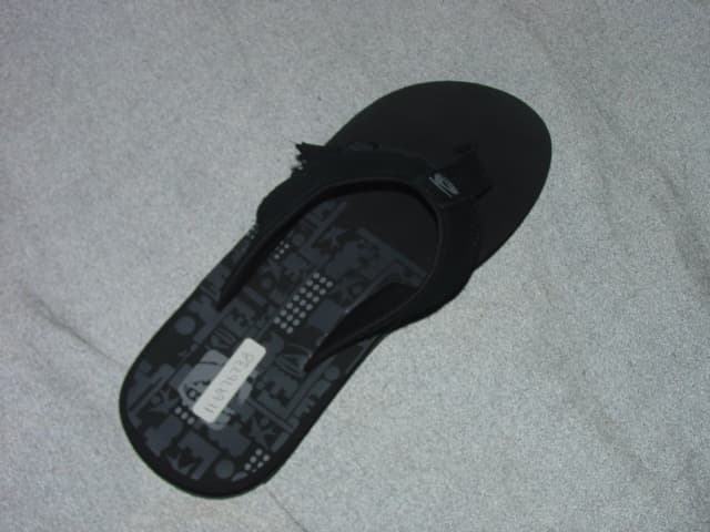 MENS FLIP FLOP. UPPER THONG OF LEATHER AND TEXTILE. LEATHER PREDOMINATES. WITH TOE POST SEPARATING THE FIRST AND SECOND TOE.  OUTER SOLE OF PLASTIC . INSOLE  LENGTH OVER 24CMS. BLACK IN COLOUR.