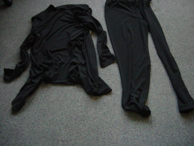 A LADIES KNITTED ENSEMBLE. CONSISTING OF TWO GARMENTS, ONE UPPER AND ONE LOWER. GARMENT ONE IS A JACKET DESIGNED TO COVER THE UPPER PART OF THE BODY FROM THE SHOULDERS TO MID THIGH MADE FROM 3 PANELS WITH LONG SLEEVES, WITH COLLAR, WITH FULL BUTTON OPENING, WITH SIDE SLITS. GARMENT TWO IS A PAIR OF TROUSERS DESIGNED TO COVER THE LOWER PART OF THE BODY FROM THE WAIST TO THE ANKLES. WITH ELASTICATED WAIST. BOTH MADE FROM THE SAME FABRIC AND SAME COLOUR. 100 PER CENT POLYESTER. HEMMED.